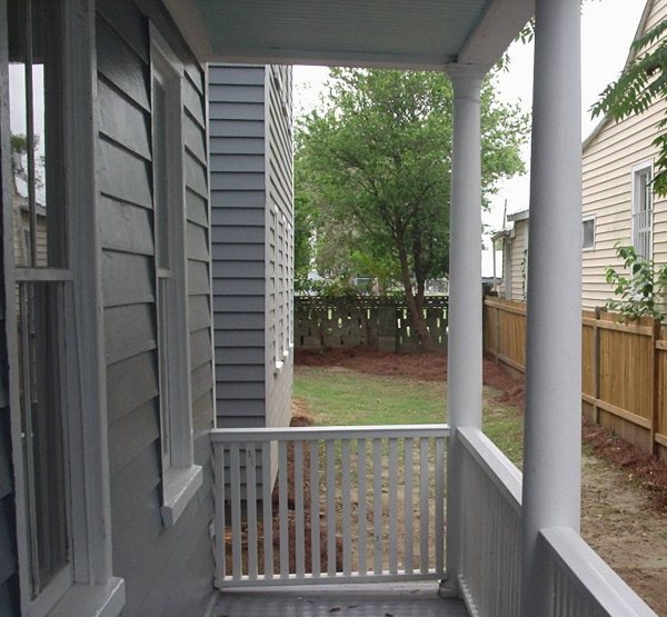 Side porch and rear yard after restoration, with privacy fence and graded grounds.