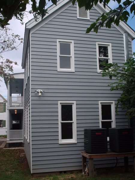 Rear gable restored, with new HVAC condensers tucked beside the chimney.