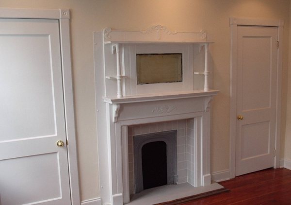 Finished parlor fireplace with carved Victorian-style mantel and overmantel mirror.