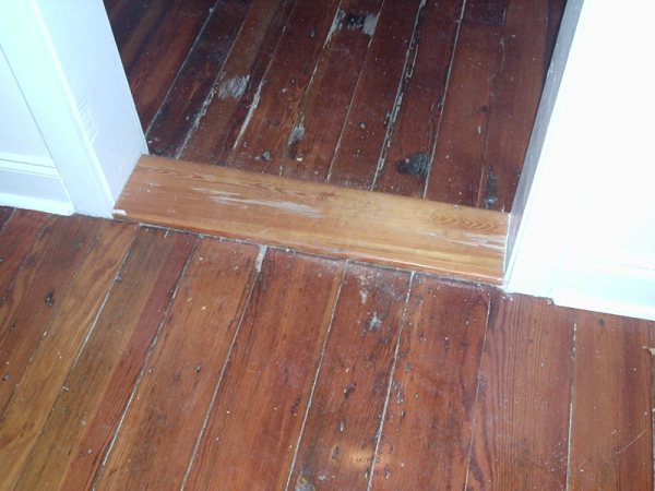 Detail of board-by-board floor patching across the threshold.