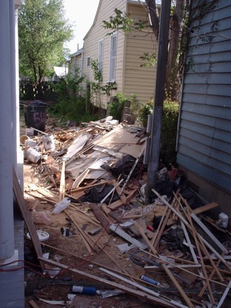 Rear side alley filled with demolition debris during gut-out.