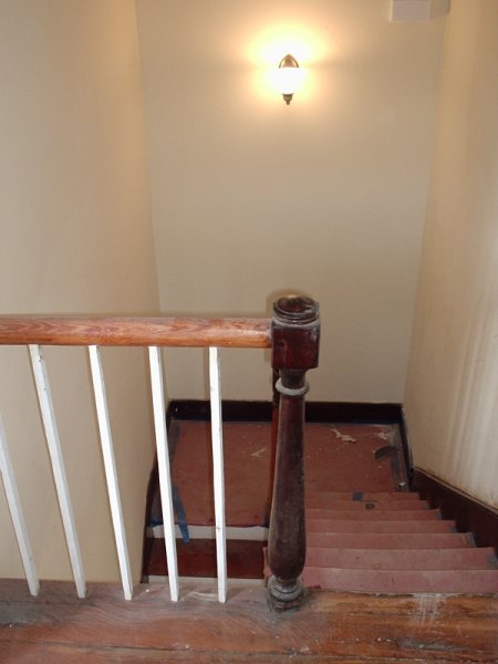 Upper landing after: period sconce, refinished newel, plaster restored.